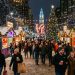 Colorful wooden vendor huts at Christmas Village Philadelphia with holiday lights and crowds at LOVE Park
