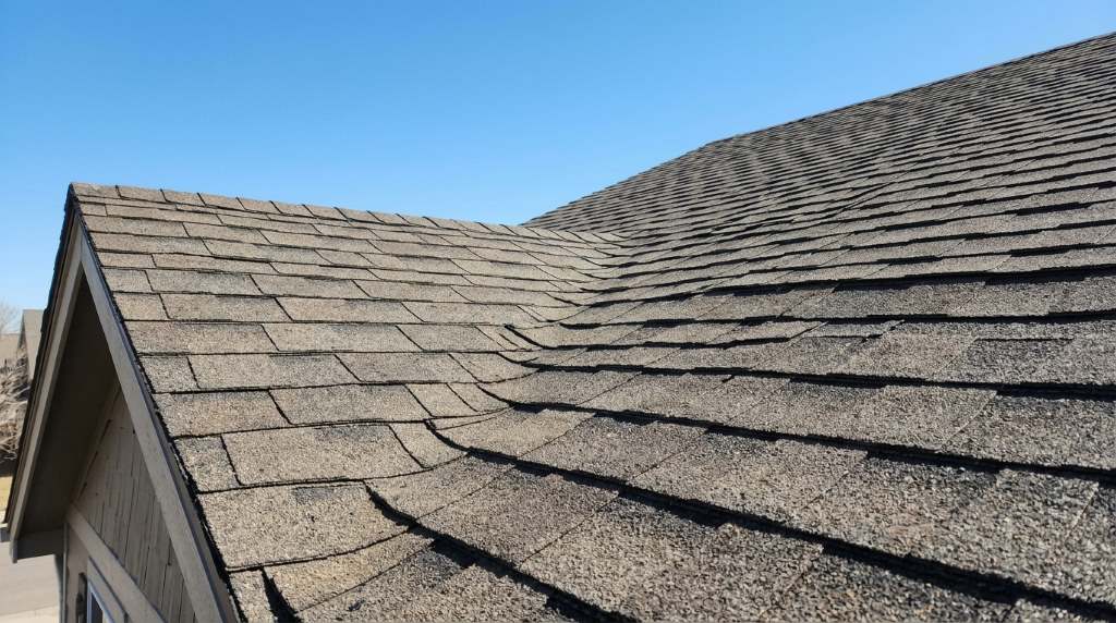 Roofing contractor inspecting wind-damaged shingles